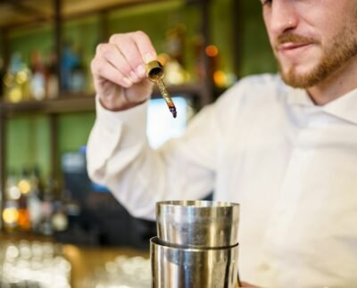 Barman adding bitters to cocktail in a modern pub