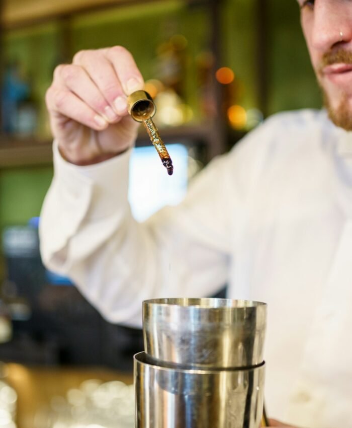 Barman adding bitters to cocktail in a modern pub